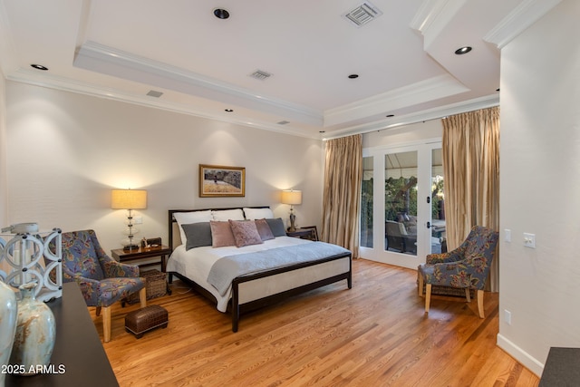 bedroom featuring ornamental molding, a tray ceiling, access to exterior, and light wood-type flooring