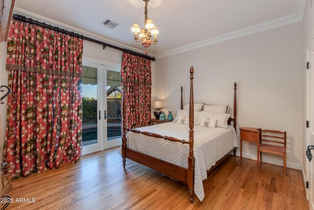 bedroom featuring wood-type flooring, a chandelier, ornamental molding, access to exterior, and french doors