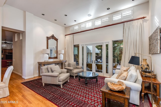 sitting room featuring ceiling fan, a towering ceiling, and light hardwood / wood-style floors