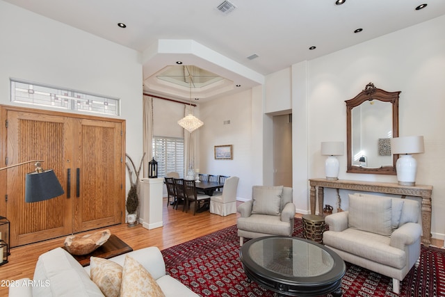 living room with a raised ceiling and light wood-type flooring