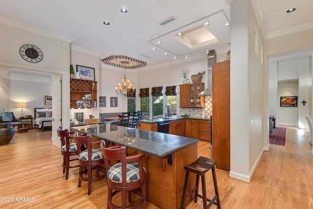 kitchen featuring ornamental molding, light wood-type flooring, pendant lighting, and a kitchen bar