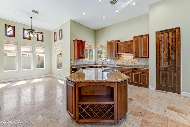 kitchen with tasteful backsplash, baseboards, a high ceiling, stone tile flooring, and a sink