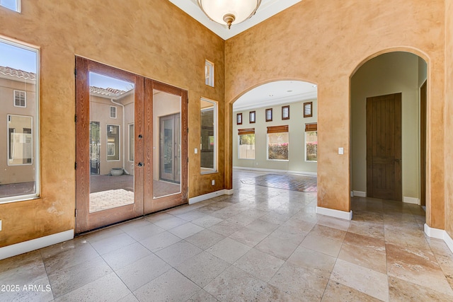 spare room featuring stone tile flooring, a high ceiling, and baseboards