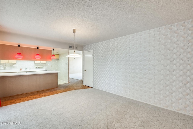15608 N 57th Dr, Glendale, AZ 85306 - kitchen with wallpapered walls, a textured ceiling, decorative light fixtures, and light countertops
