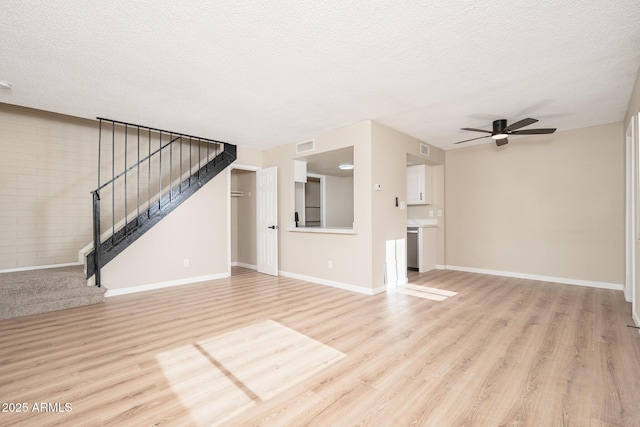 unfurnished living room with ceiling fan, light wood-type flooring, and a textured ceiling