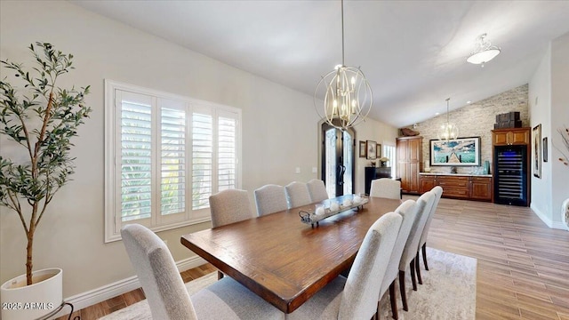 dining space with vaulted ceiling, a notable chandelier, and light wood-type flooring