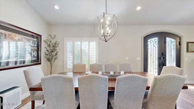 dining area featuring french doors, plenty of natural light, an inviting chandelier, and light hardwood / wood-style flooring