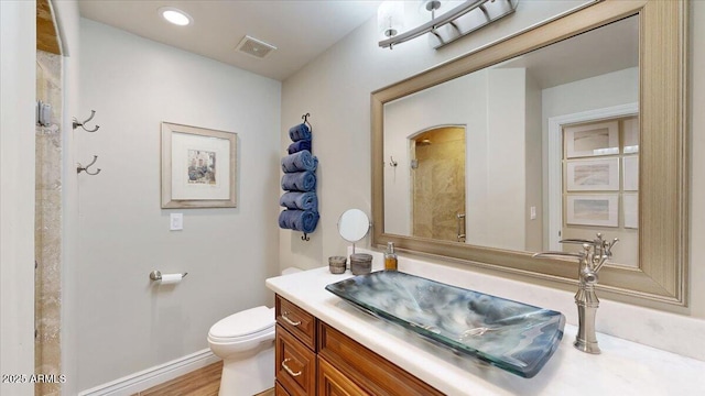 bathroom with hardwood / wood-style flooring, vanity, a shower, and toilet