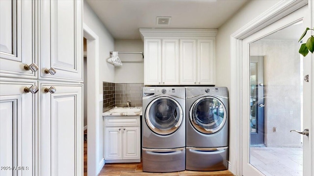 washroom featuring cabinets, sink, washer and clothes dryer, and light hardwood / wood-style floors