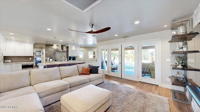 living room featuring french doors, ceiling fan, and light wood-type flooring