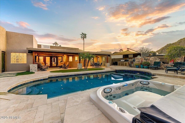 pool at dusk with a jacuzzi and a patio