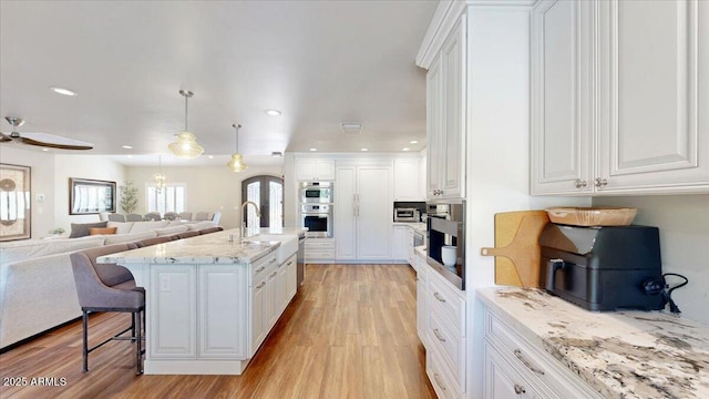 kitchen with white cabinetry, hanging light fixtures, and an island with sink