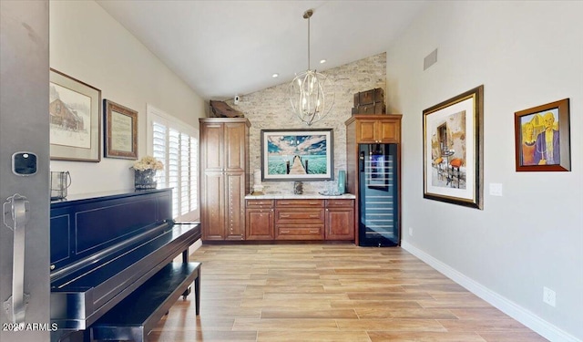 interior space featuring a notable chandelier, high vaulted ceiling, beverage cooler, and light wood-type flooring