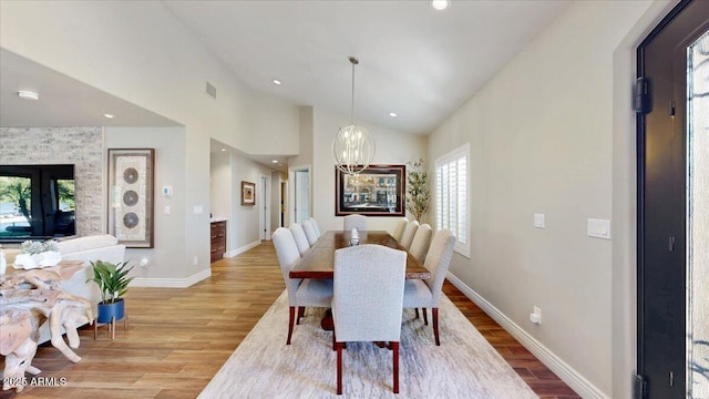 dining area with a chandelier, high vaulted ceiling, and light wood-type flooring