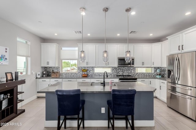 kitchen with stainless steel appliances, a sink, decorative backsplash, a kitchen bar, and white cabinetry
