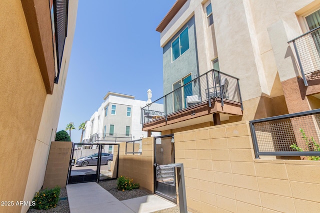 view of property exterior with a gate, stucco siding, fence, and a balcony