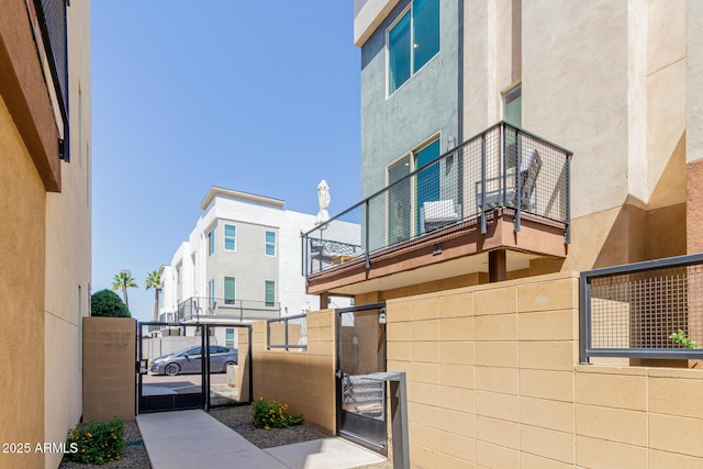 view of side of home with a gate, stucco siding, and fence