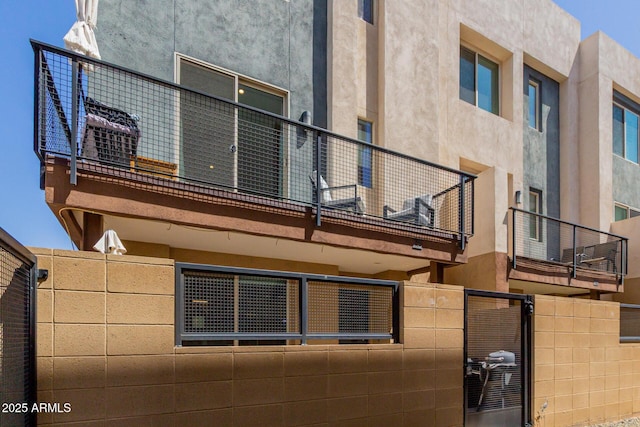view of property exterior with stucco siding, fence, and a balcony