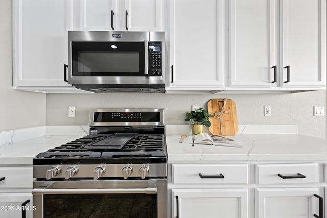 kitchen featuring appliances with stainless steel finishes, white cabinets, and light stone counters