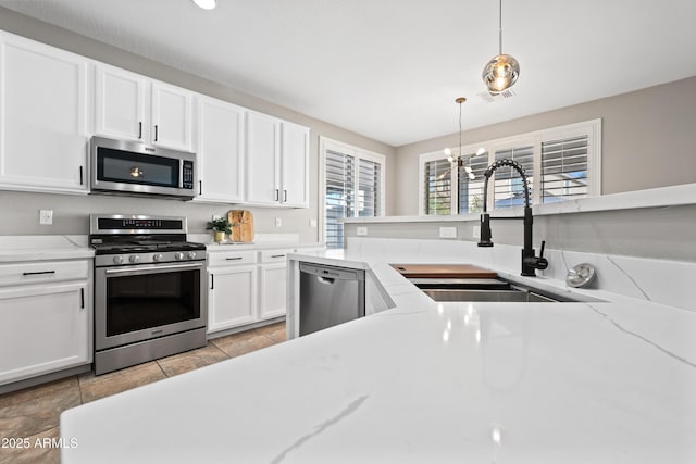 kitchen featuring white cabinetry, sink, hanging light fixtures, light stone counters, and stainless steel appliances