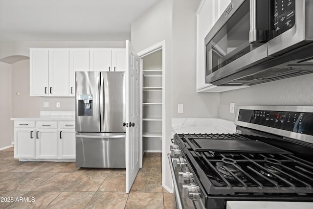 kitchen featuring light stone counters, white cabinets, and appliances with stainless steel finishes