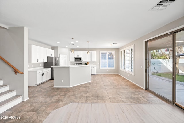 kitchen featuring white cabinetry, a center island, light tile patterned floors, pendant lighting, and stainless steel appliances