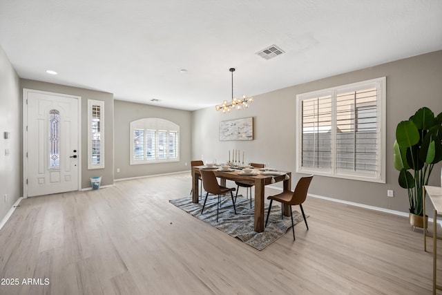 dining area with a healthy amount of sunlight, an inviting chandelier, and light hardwood / wood-style flooring