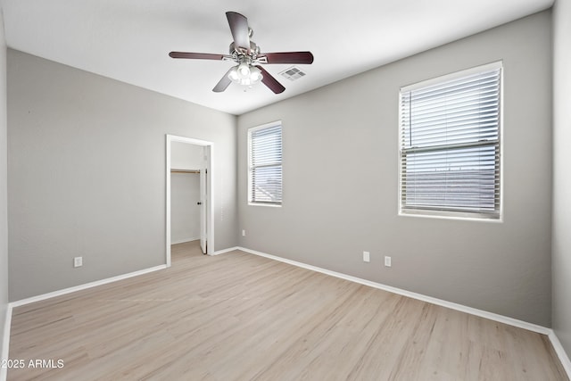 unfurnished bedroom with ceiling fan, a spacious closet, light hardwood / wood-style floors, and a closet