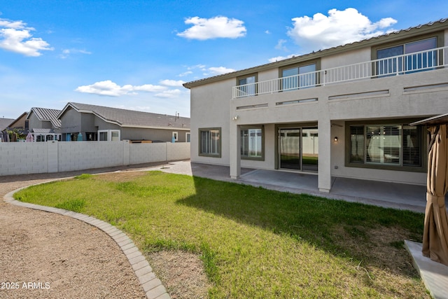 back of property featuring a patio area, a balcony, and a lawn