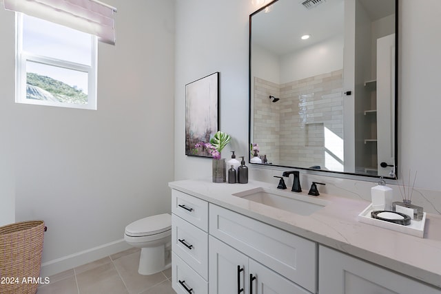 bathroom featuring a tile shower, tile patterned flooring, vanity, and toilet