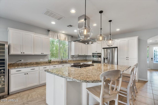 kitchen featuring sink, stainless steel appliances, a center island, white cabinets, and decorative light fixtures