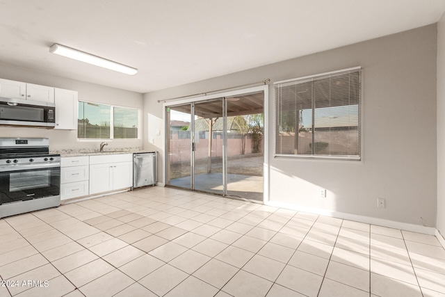 kitchen featuring light tile patterned floors, light stone counters, stainless steel appliances, and white cabinets