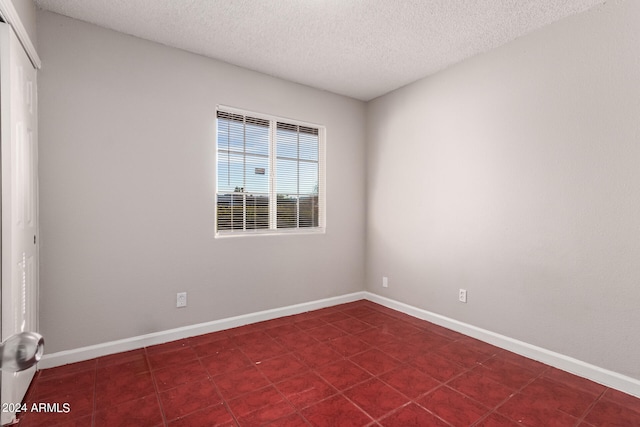 empty room featuring dark tile patterned floors and a textured ceiling