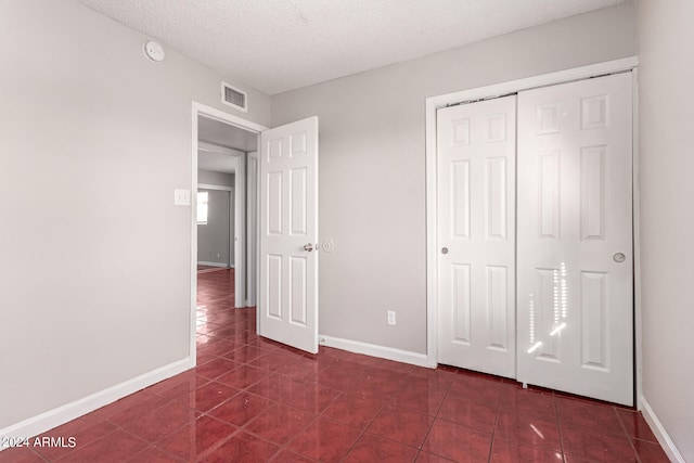 unfurnished bedroom featuring a closet, dark tile patterned floors, and a textured ceiling