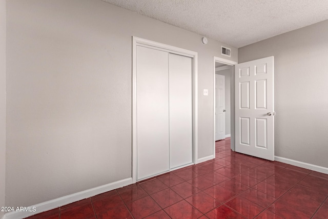 unfurnished bedroom featuring tile patterned floors, a closet, and a textured ceiling