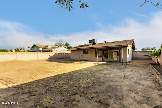 back of property with central AC unit and a patio