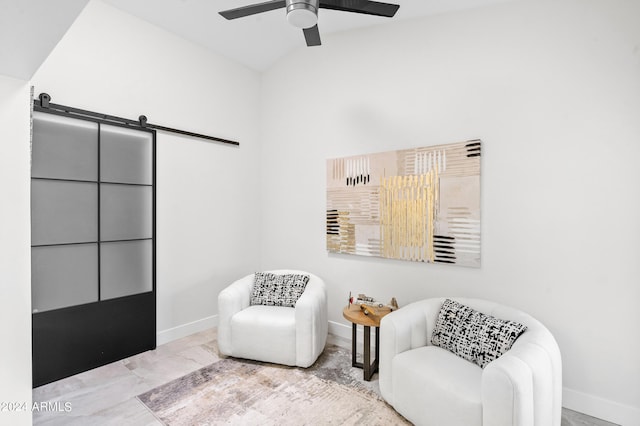 sitting room with ceiling fan, marble finish floor, a barn door, and baseboards