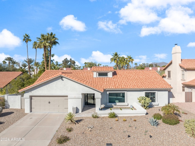 mediterranean / spanish-style home with a tile roof, an attached garage, driveway, and stucco siding