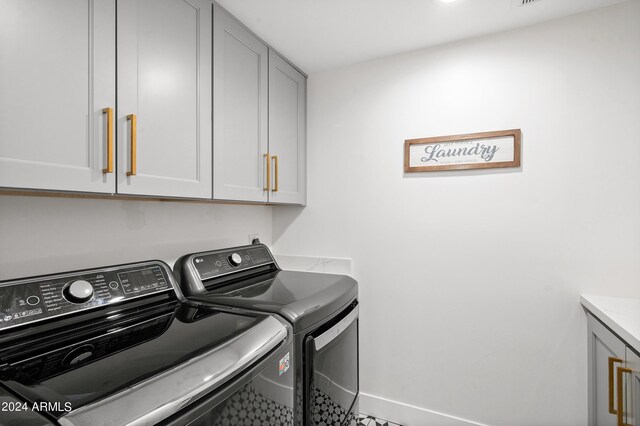 laundry area with washing machine and clothes dryer, baseboards, and cabinet space