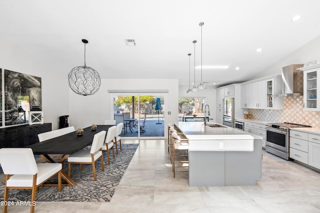 kitchen with high end range, wall chimney range hood, visible vents, a kitchen island with sink, and a sink
