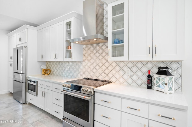 kitchen with light countertops, backsplash, white cabinetry, wall chimney exhaust hood, and appliances with stainless steel finishes