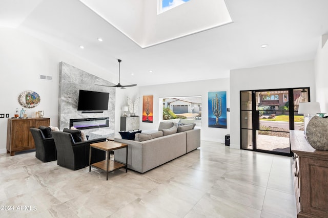 living area with visible vents, a ceiling fan, a towering ceiling, and a high end fireplace
