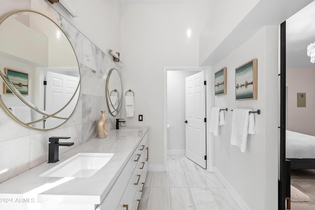 full bathroom with tasteful backsplash, double vanity, ensuite bath, marble finish floor, and a sink