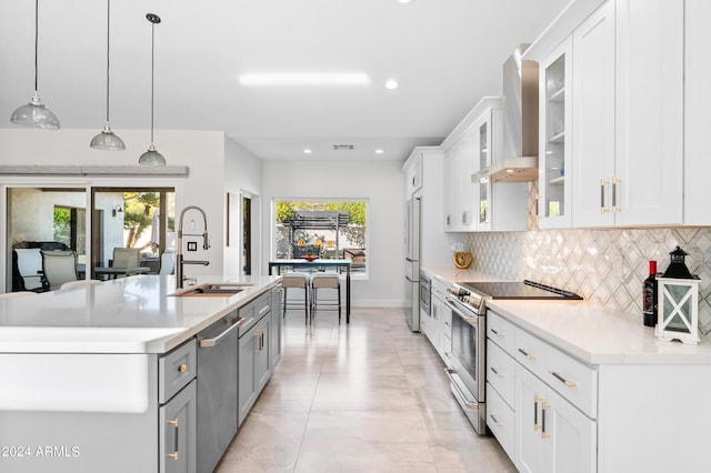 kitchen featuring wall chimney range hood, decorative backsplash, a sink, and appliances with stainless steel finishes