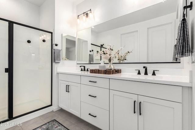 bathroom with tile patterned floors, double vanity, a stall shower, and a sink