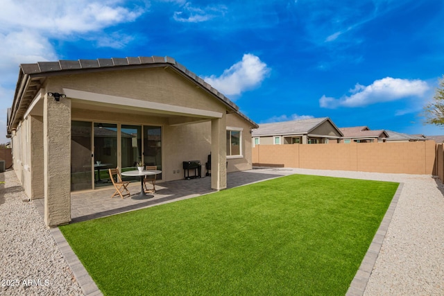 rear view of house featuring a patio area, stucco siding, a yard, and a fenced backyard