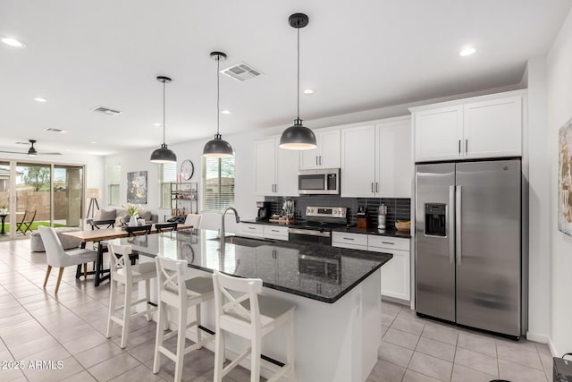 kitchen featuring tasteful backsplash, visible vents, light tile patterned floors, stainless steel appliances, and a sink