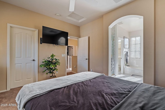 bedroom with ensuite bathroom and light carpet