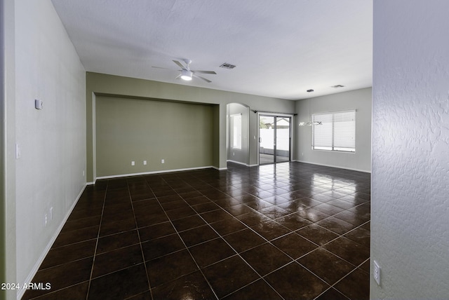 empty room featuring ceiling fan and dark tile patterned flooring