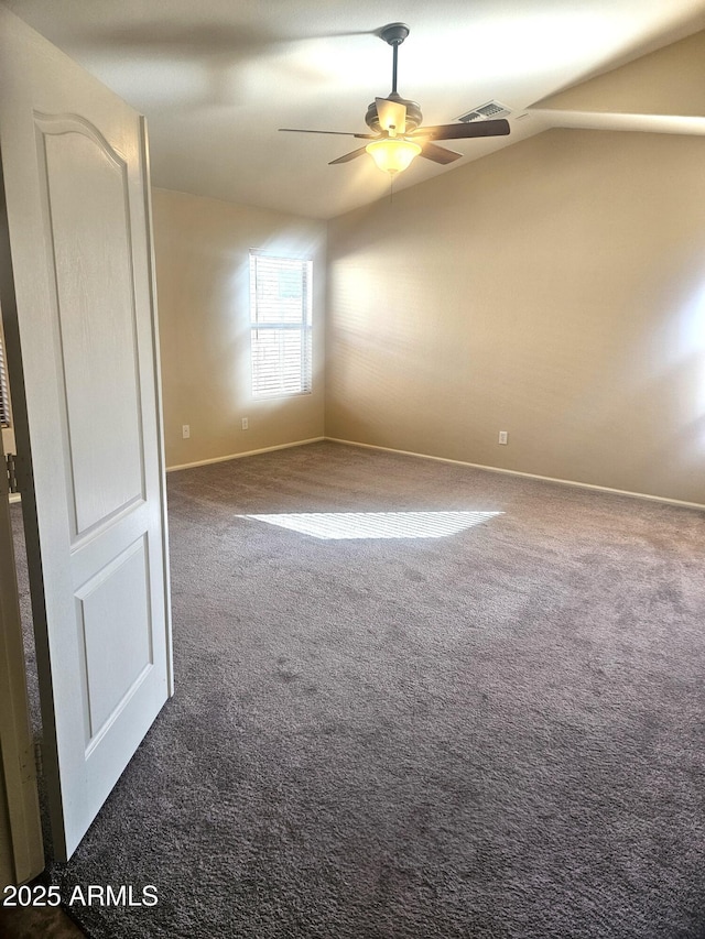 empty room with vaulted ceiling, ceiling fan, and dark carpet